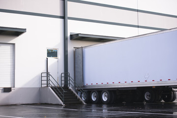 Dry van semi trailer loading and unloading commercial cargo in warehouse dock