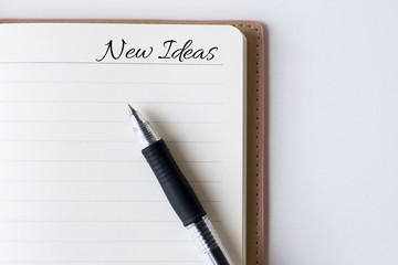 Conceptual,notebook on a white table. open diary and pen with new ideas words