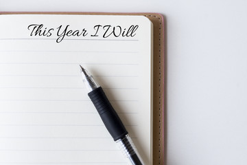 Conceptual,notebook on a white table. open diary and pen with this year i will words