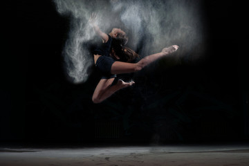 Dancing girl in a jump with dust powder