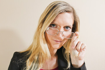 Beautiful young woman with glasses on ochre background