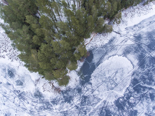 Flight over frozen lake breaking ice in rural village, Lithuania. Aerial photography during winter season.