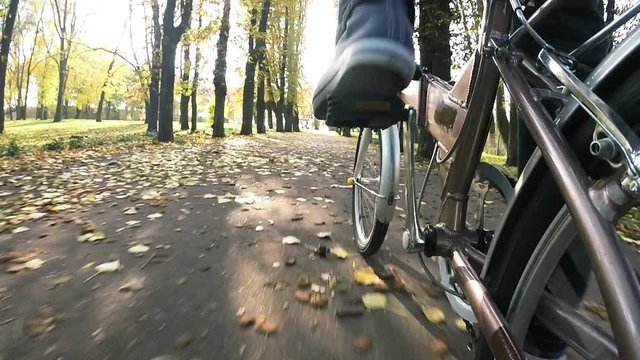 

Point of view camera filming. Man  goes by bicycle on city sunny  autumn park
