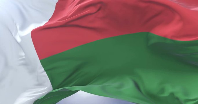 Flag of Madagascar waving at wind in slow in blue sky, loop