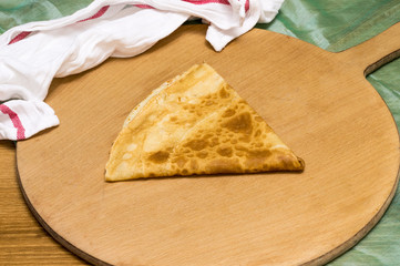 Folded crepe, Russian blini on wooden cutting board with white cloth