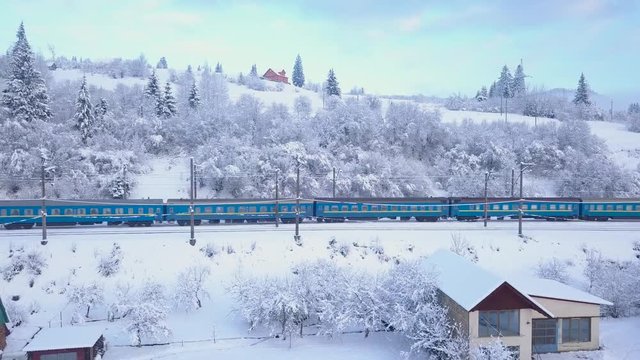 Aerial view of the train going through the mountainous terrain in winter