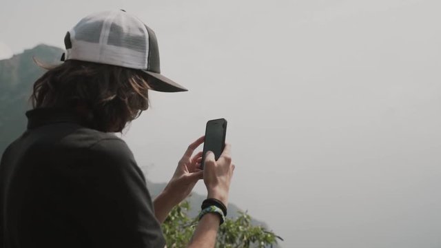 Young man taking photo of Machu Picchu, view from the back. Mountains of Machu Picchu.Tourists on Machu Picchu.