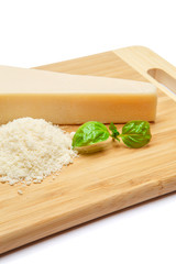 a piece of Parmesan and grated cheese on cutting board white background