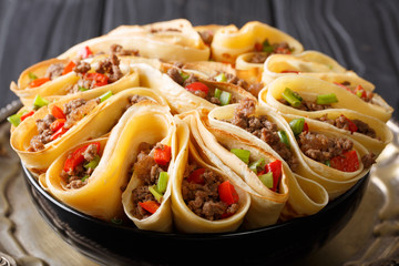 Delicious crepes stuffed with beef meat, peppers and onions closeup. horizontal
