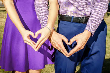 Valentine's day in trendy color is ultra violet. The hands of man and woman show a sign of heart, the love of a young couple on the first date. Stylish women's dress in trend color. Family look.