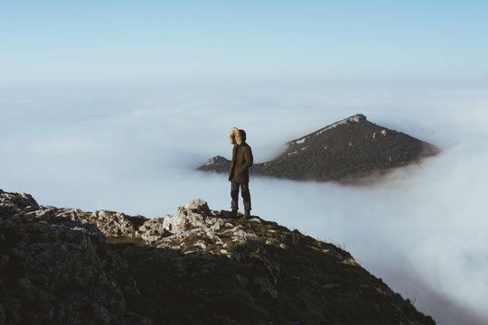 Man on rocky cliff in clouds