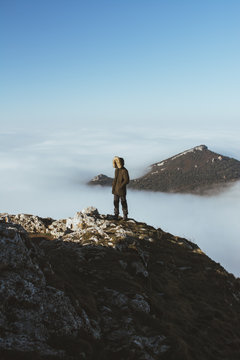 Man on rocky cliff in clouds