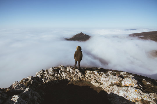 Man on rocky cliff in clouds