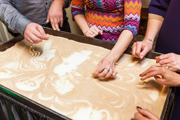 men and women paint their hands on the sand, sand animation. people draw on the sand
