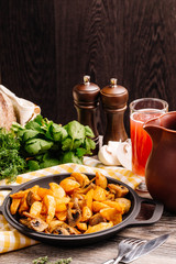 potatoes in a pan with mushrooms  on a wooden table. vegetarian food concept