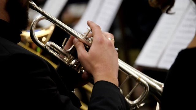 A musician is playing on a trumpet, with several other musicians beside him...