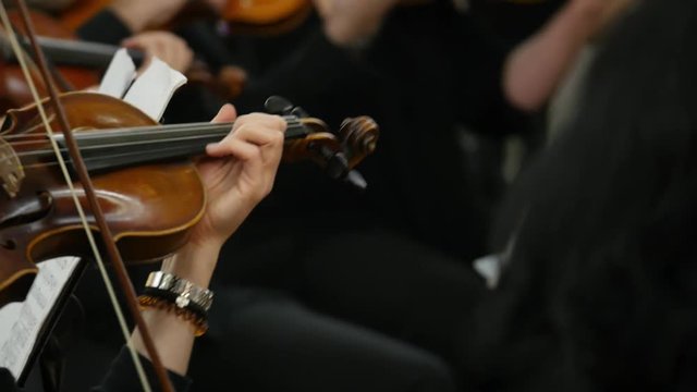 Close up footage of a person playing on a violin together with other violin players...