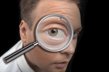 portrait of a man looking in a magnifying glass