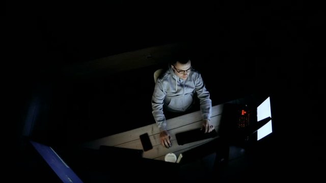 Young Hacker Breaks into Corporate Data Servers from His Underground Hideout. Place Has Dark Atmosphere, Multiple Displays. top view