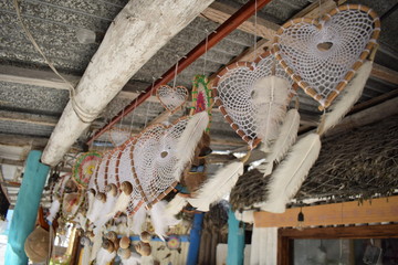 Several hanging white flying heart dreamcatchers in a row with feathers in the wind