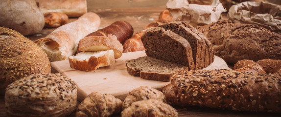 Various baked breads and rolls on rustic wooden table