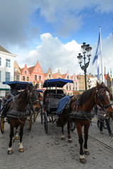 Fototapeta premium Paseo en cocoche de caballos en Brujas, ciudad de canales y puentes belga , capital de Flandes Occidental, al noroeste de Bélgica, Europa