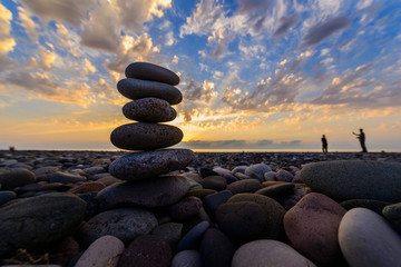 Stones pyramid on sand symbolizing zen, harmony, balance. Black sea at sunset in the background.