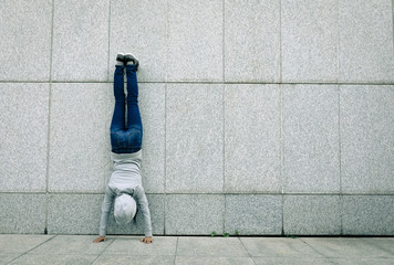 female hipster doing a handstand against wall