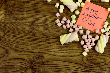 A sticker with Text: Happy valentine's day decorated with marshmallow sweets. love concept on wooden background.