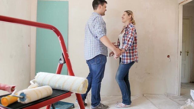 Slow motion footage of happy young married couple hugging at new apartment under renovation