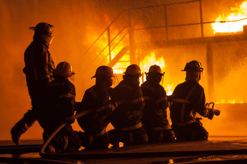 Fire chief and firefighters in front of burning structure during firefighting exercise
