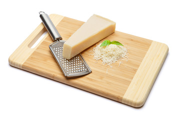 a piece of Parmesan and grated cheese on cutting board white background