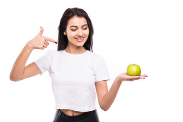 Portrait of a smiling pretty girl holding an apple and pointing finger over white background