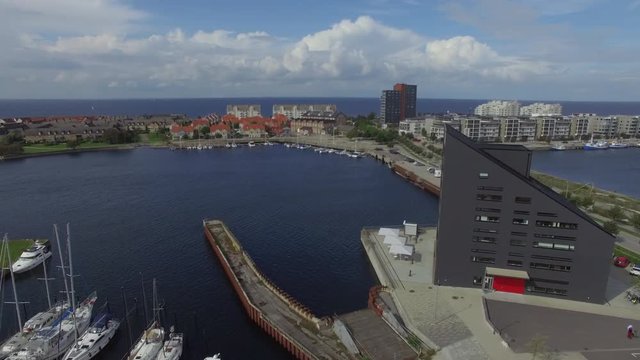 Aerial view of coastal residential area in Malmö, Sweden. Drone shot flying up over island, apartment buildings and sea coastline