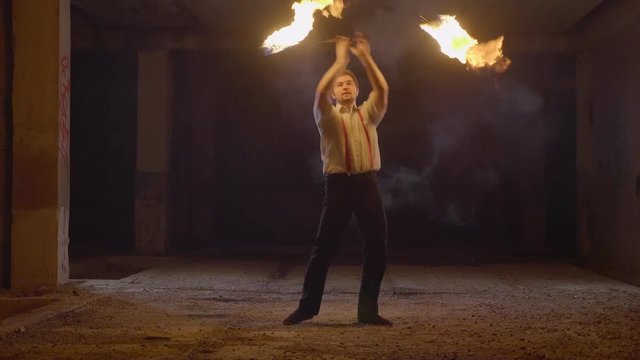 Male artist performing fire show at dark in slow motion.