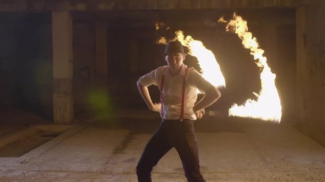Male artist performing fire show at dark in slow motion.