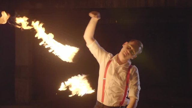 Male artist performing fire show at dark in slow motion.