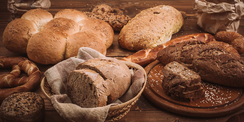 Various baked breads and rolls on rustic wooden table