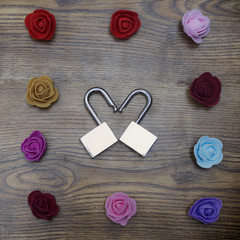 Gift box and two locks in shape of heart with roses on wooden table. Symbol of Valentine's day. Top view.