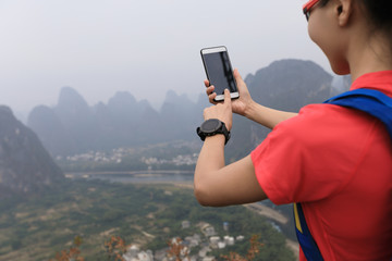 successful backpacker taking photo with smartphone on the top of  mountain