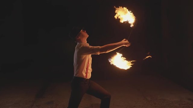 Male artist performing fire show at dark in slow motion.