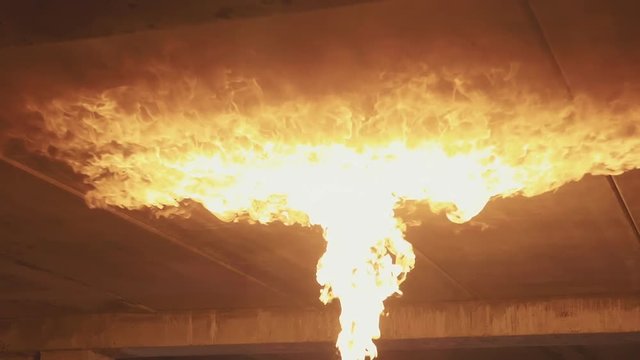 Fire on the ceiling from flamethrower at dark in slow motion.