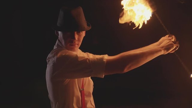 Male artist performing fire show at dark in slow motion.