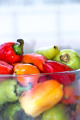 red , green and yellow peppers in a transparent bowl