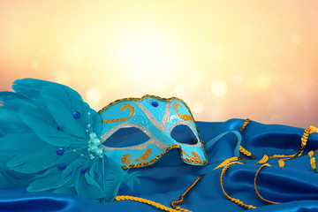 Image of elegant blue and gold venetian mask over blue silk fabric background.