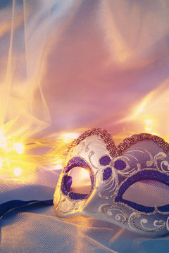 Image of delicate elegant venetian mask over blue silk and tulle fabric background.
