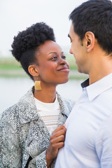 Side view of young happy couple who standing in embrace and looking at each other outdoors