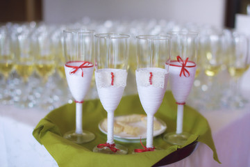 Full glasses of bubbly or champagne with four decorated ones separated on a green tray, for the bride, groom and witnesses, a typical wedding reception or party welcome for the guests