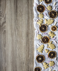 wooden table, and on the right are laid out on white cloth gingerbread cakes as a tree of hearts of hares of little people of bears and stars, dried orange and marshmallow slices 