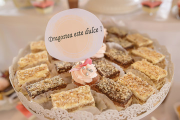 White metal tray with square cakes and one cupcake with the message in Romanian 